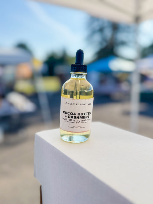 Bottle of 'Cocoa Butter & Cashmere' product on a white surface with a blurred outdoor background
